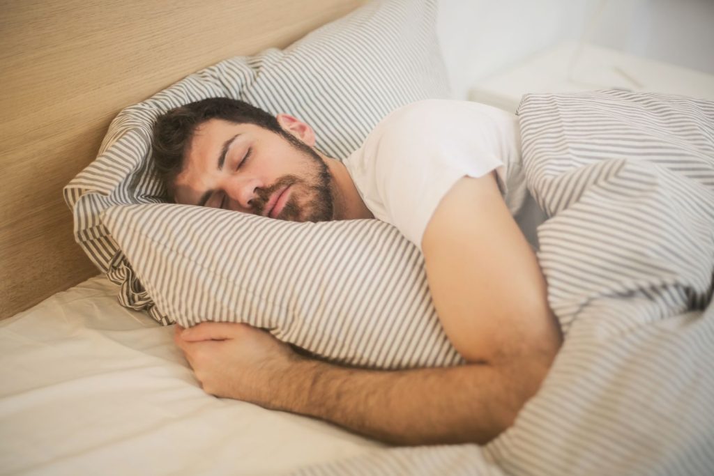 Man asleep in bed, illustrating the importance of healthy sleep