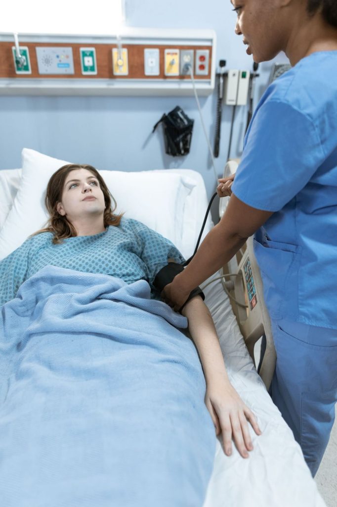 Patient resting in bed while a clinician checks on her during sleep evaluation